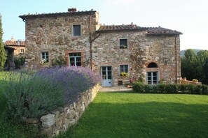 A stone building with a garden in front, featuring a stone wall and lavender plants. - Barbazzano: a superb Tuscan villa perfect for group getaways (Toscana)