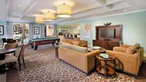 A spacious living area with a pool table, comfortable seating, and a television.