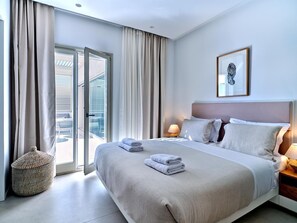 Et moderne hotelværelse med en stor seng, et natbord med lampe, et vindue med gardiner og udsigt udad.
