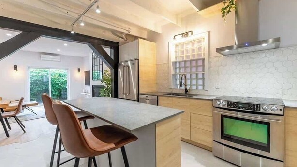 A modern kitchen with a central island, stainless steel appliances, and a hexagonal tile backsplash.