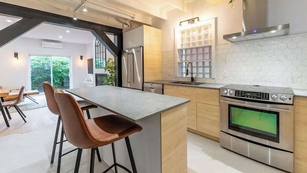 A modern kitchen with a central island, stainless steel appliances, and a hexagonal backsplash.
