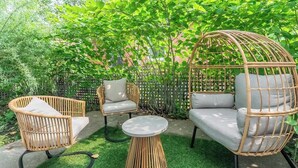 A garden patio with wicker furniture, a round table, and a decorative hanging chair.