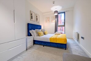 A bedroom with a bed, nightstands, a wardrobe, and artwork on the walls. - Central Manchester Townhouse + Free Parking. (Manchester)