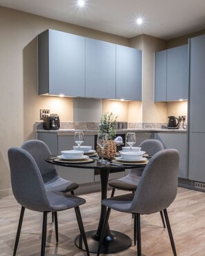 A modern dining area with a round table, four chairs, and a central vase. - Central Manchester Townhouse + Free Parking. (Manchester)