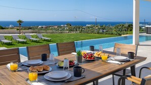 A dining table set for breakfast with a pool view, including plates, glasses, and croissants. - White Stone Elegance with Pool, Jacuzzi & Golden Sunsets (Chania)