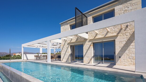 A modern poolside area with a clear view of the sea, stone walls, and a covered seating area. - White Stone Elegance with Pool, Jacuzzi & Golden Sunsets (Chania)