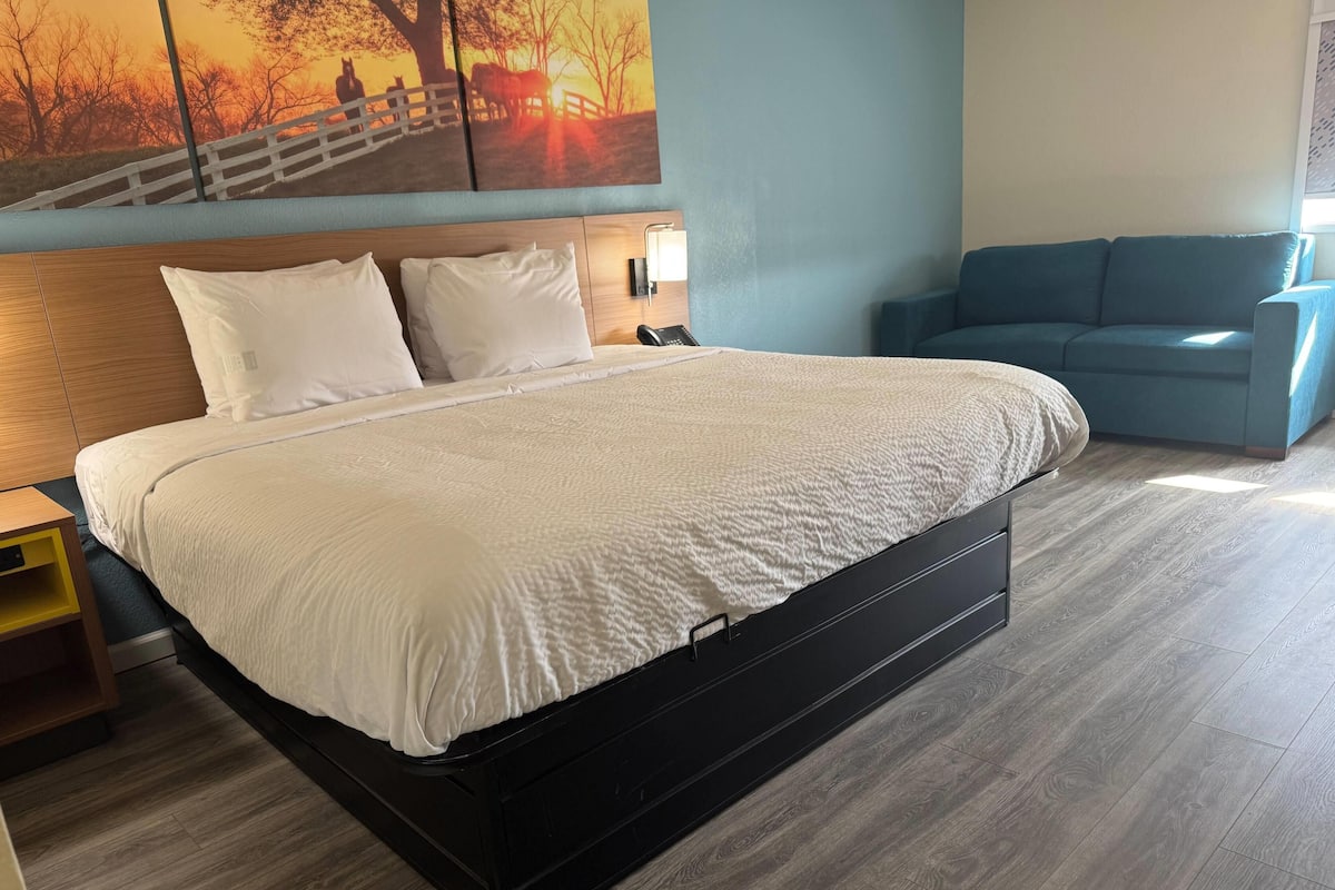 Un lit avec une couette blanche, une tête de lit en bois et une table de chevet avec une lampe.