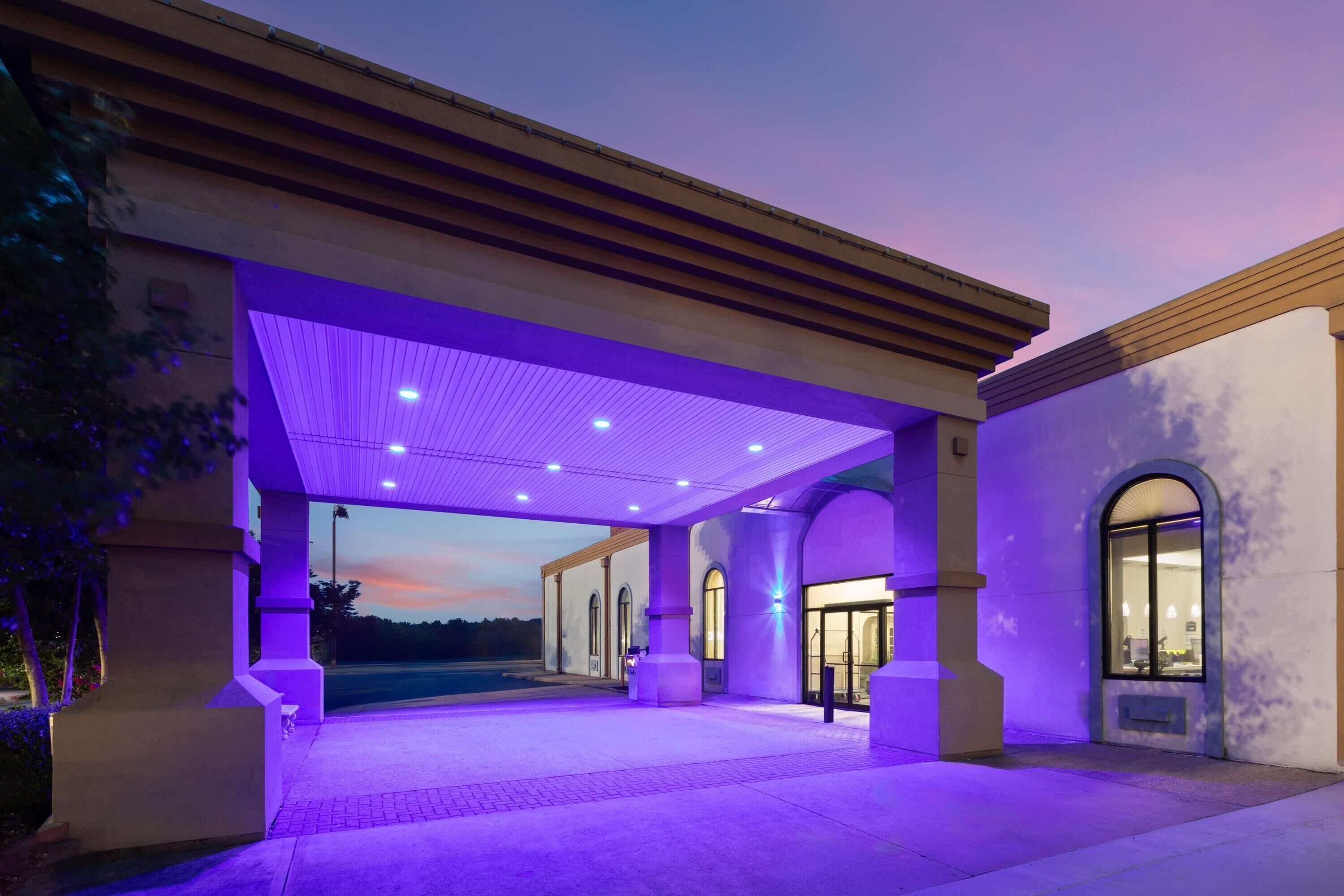 A building with a covered entrance, columns, and a view of the sky.