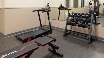 A gym with treadmills, a bench, and a rack of dumbbells.