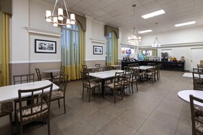 A restaurant with multiple tables and chairs, a counter with a coffee machine, and framed pictures on the walls. - Days Inn & Suites By Wyndham Festus (Festus)