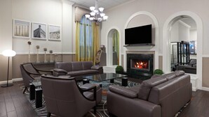 Een moderne woonkamer met een hoekbank, een glazen salontafel en een open haard.