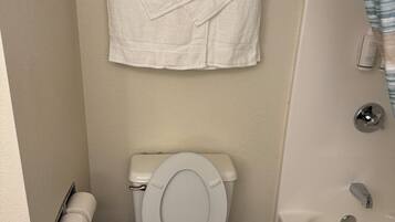 A bathroom with a toilet, a bathtub, and a towel rack with folded towels.
