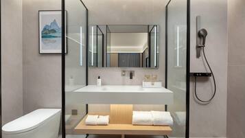 A modern bathroom with a glass-enclosed shower, a white sink, and a wooden bench with towels.