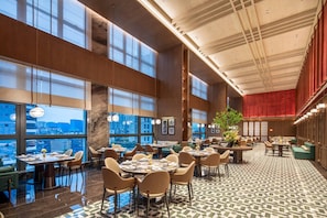 A spacious dining area with high ceilings, large windows, and a variety of seating arrangements. - Wyndham Fuzhou Gulou (Fuzhou)