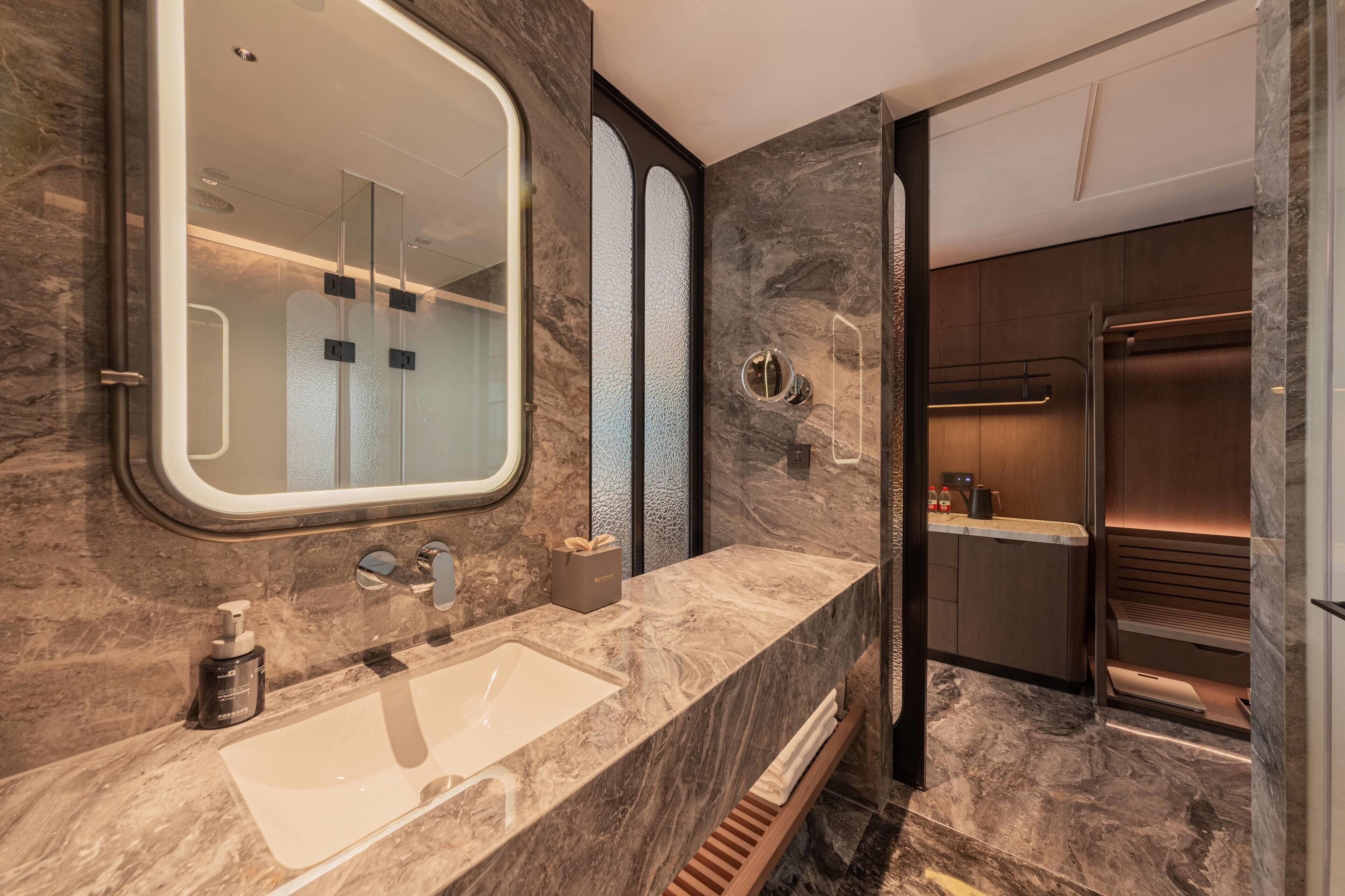 Une salle de bain moderne avec un grand miroir, un lavabo et un espace douche.