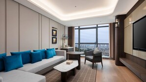 A modern living room with a sofa, armchairs, a coffee table, a TV, and a large window offering a city view. - Wyndham Fuzhou Gulou (Fuzhou)