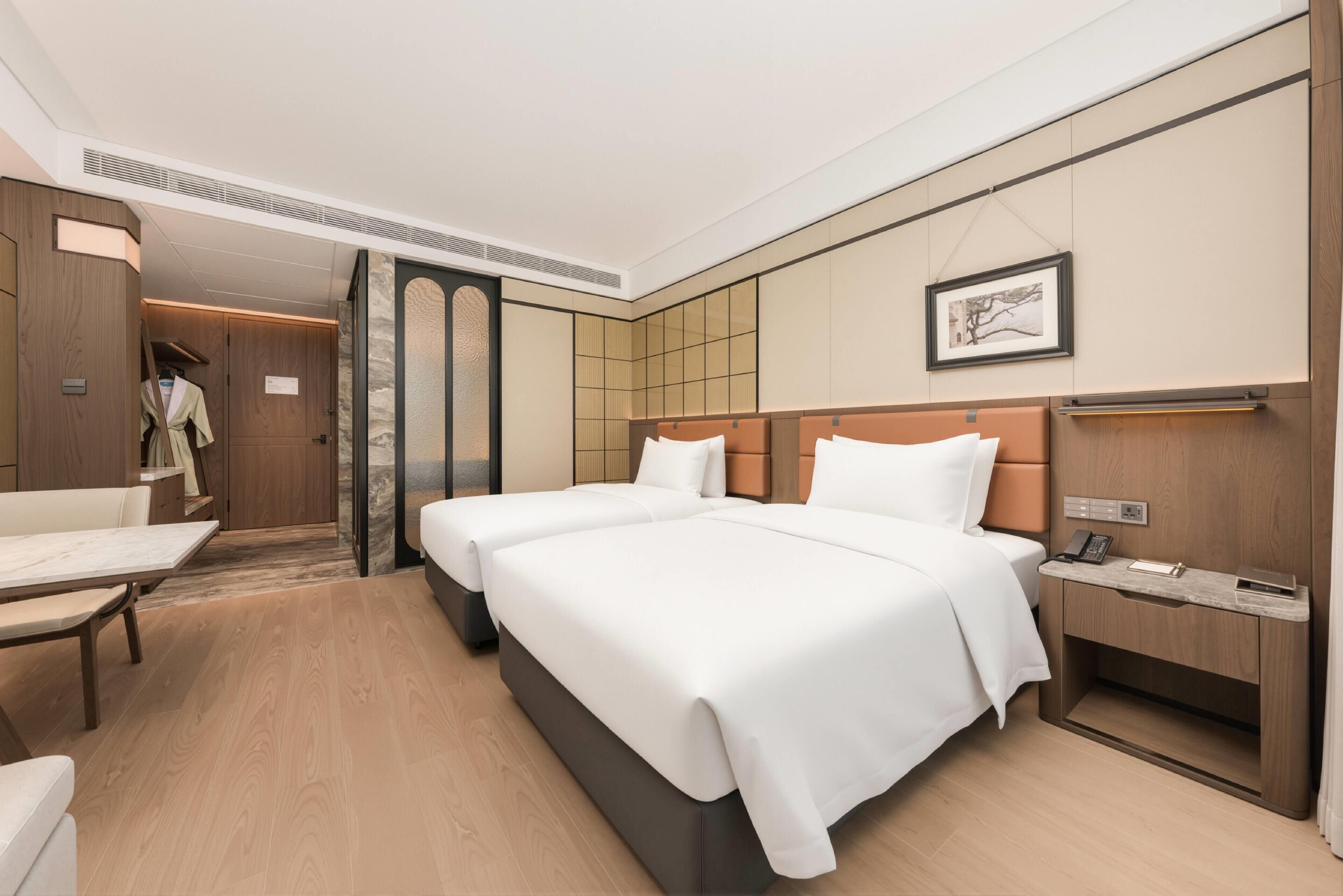 Ein Hotelzimmer mit zwei Betten, einem Schreibtisch, einem Stuhl und einem Kleiderschrank.