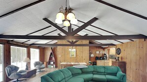 Een knus interieur van een chalet met een groene modulaire bank, houten vloeren, een eethoek en een keuken.