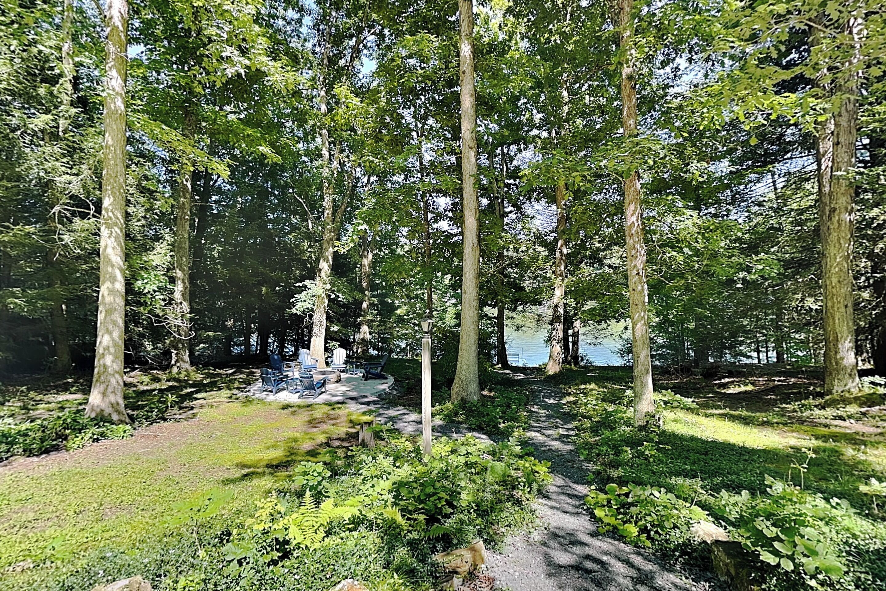 Een bebost gebied met een duidelijk pad dat leidt naar een zitgedeelte met stoelen en tafels.