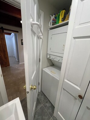 A laundry room with a washing machine, a dryer, and a shelf with cleaning supplies. - Lakefront Cottage, Private dock, Near ballparks (Roach)