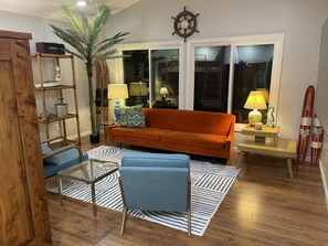 A living room with a sofa, a coffee table, a lamp, a plant, and a wooden ladder. - Lakefront Cottage, Private dock, Near ballparks (Roach)