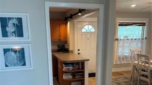 A hallway leading to a kitchen with wooden cabinets and a built-in bookshelf. - The Blue Retreat in Fort Myers Beach (Fort Myers Beach)