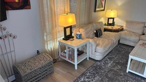 A cozy living room with a sofa, two side tables with lamps, a bench, and a patterned rug. - The Blue Retreat in Fort Myers Beach (Fort Myers Beach)