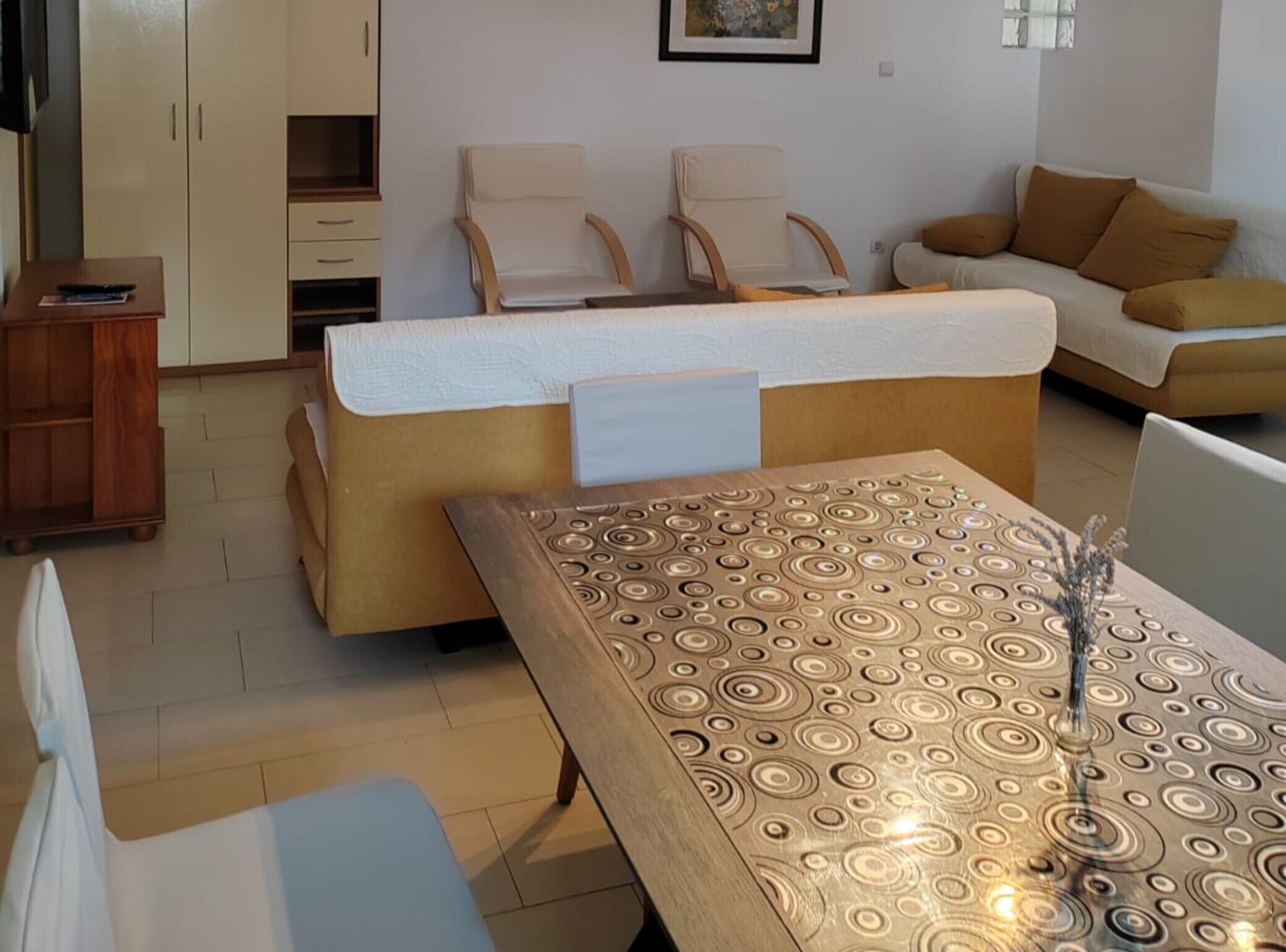 A living room with a sofa, two chairs, a wooden table, and a cabinet.
