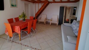 A dining area with a table and chairs, a staircase, a sofa, and a small cabinet. - Apartments Lighthouse -(A4) - TwoBedroom Apartment with Sea View (Fazana)