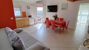 A living room with a sofa and a dining area with a table and chairs. There is a kitchen area with a microwave and a sink. - Apartments Lighthouse -(A4) - TwoBedroom Apartment with Sea View (Fazana)