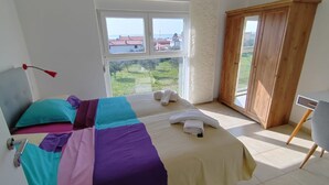 Een hotelkamer met twee bedden, uitzicht op zee en een houten garderobe.
