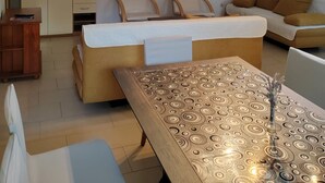 Een woonkamer met een bank, twee stoelen, een houten tafel en een kast.