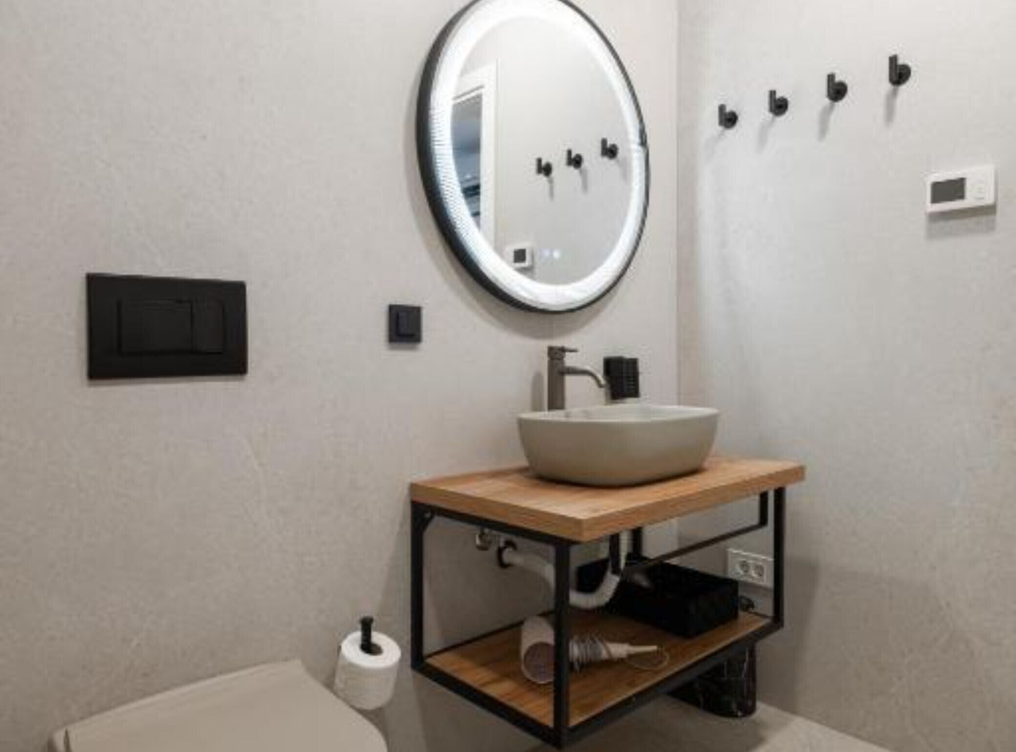 Ein modernes Badezimmer mit einem runden Spiegel, einem weißen Waschbecken und einer Toilette.