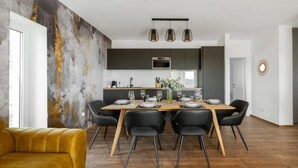 Un espace repas moderne avec une table en bois dressée pour six personnes, des chaises noires et un fauteuil jaune.