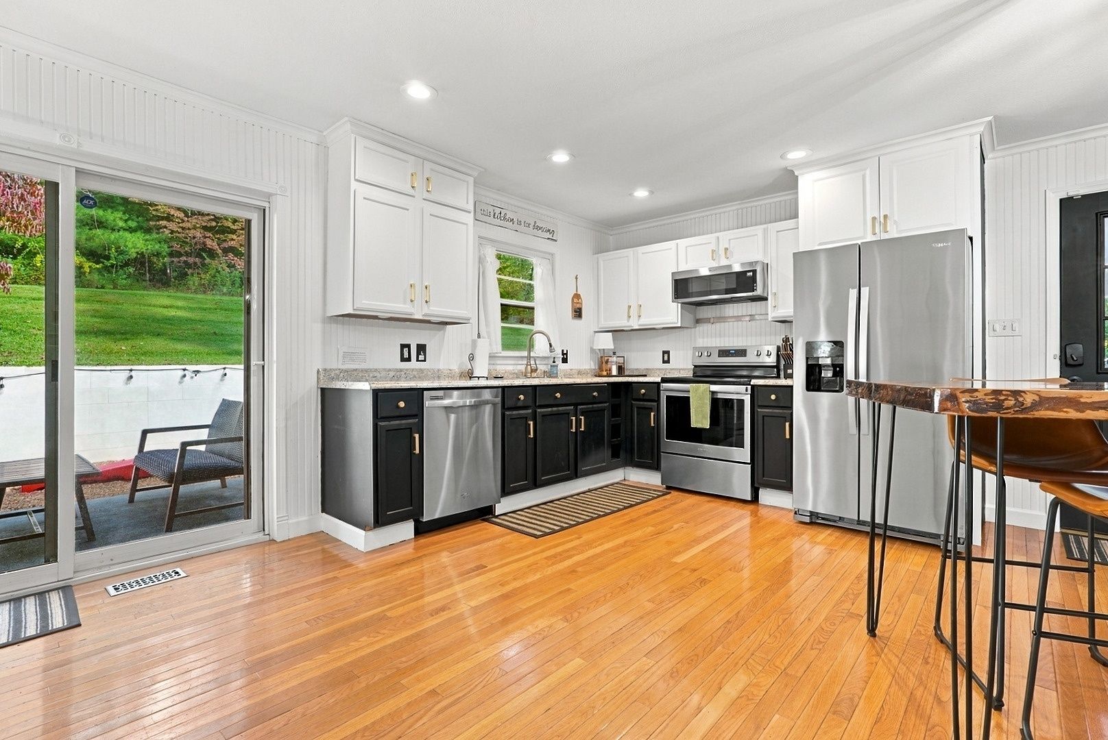 Una cocina moderna con armarios blancos, electrodomésticos de acero inoxidable y piso de madera.