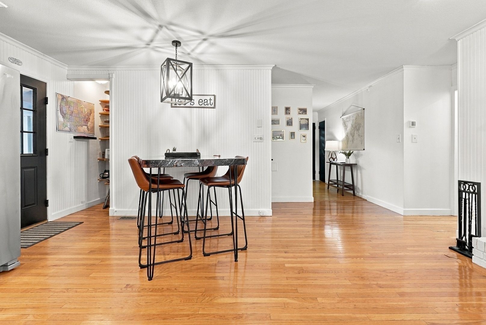 A spacious dining area with a wooden floor, a table with four chairs, and a hanging light fixture.