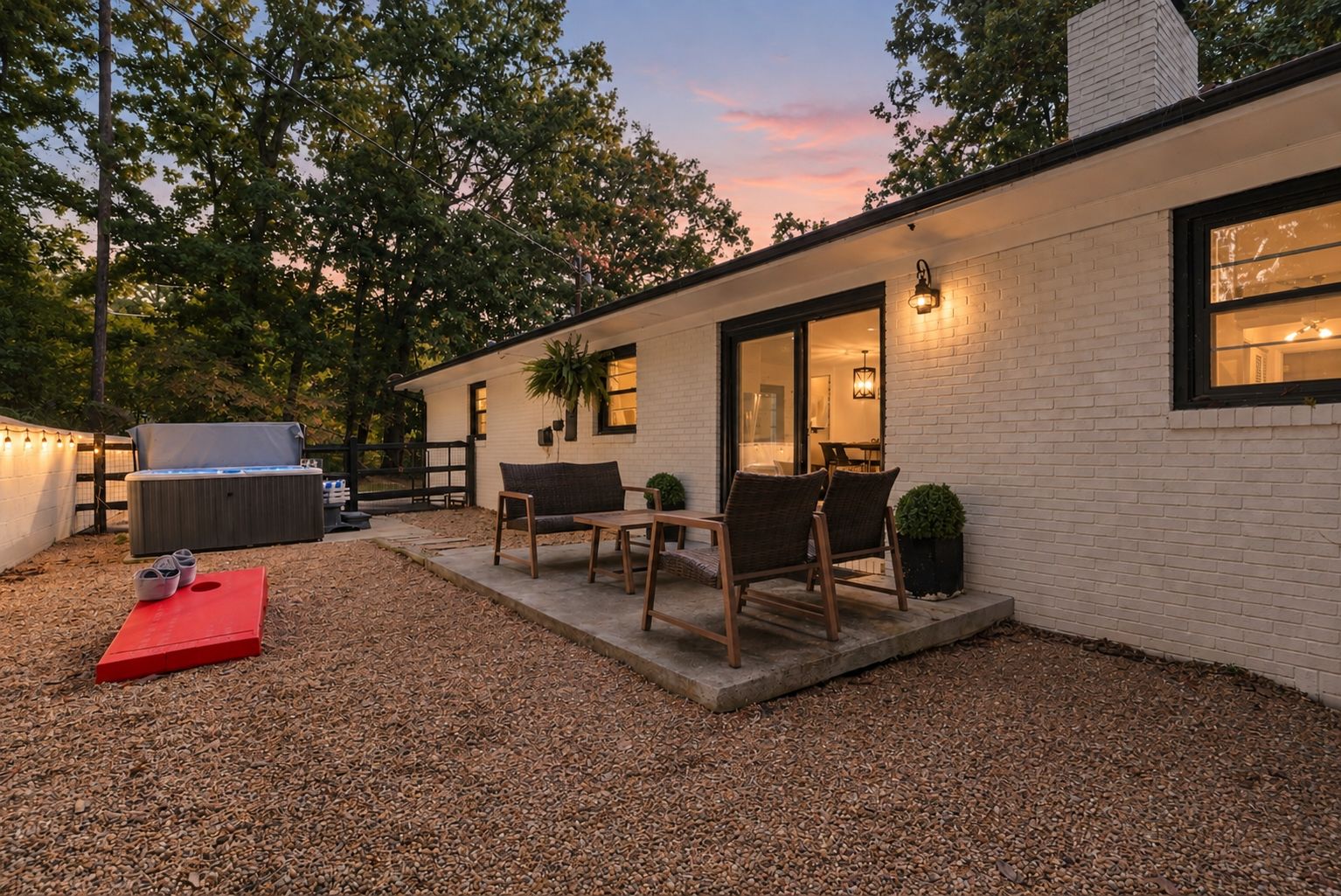 A modern outdoor patio with a hot tub, seating area, and a covered table.