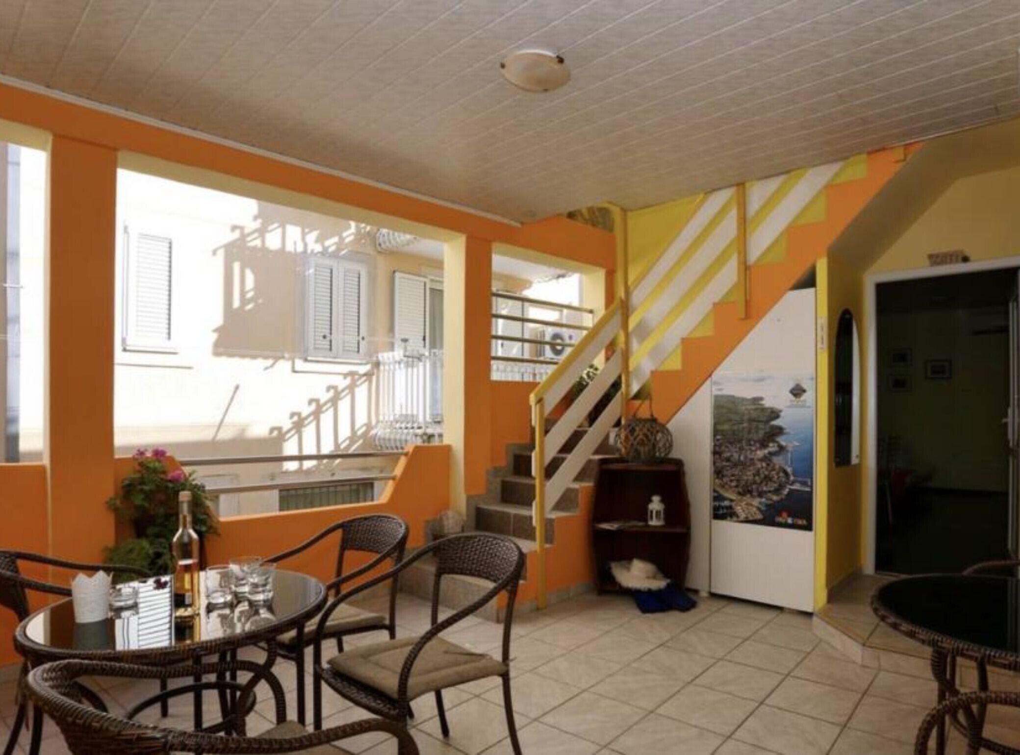 A dining area with wicker furniture, a table set for two, and a view of the outside balcony.