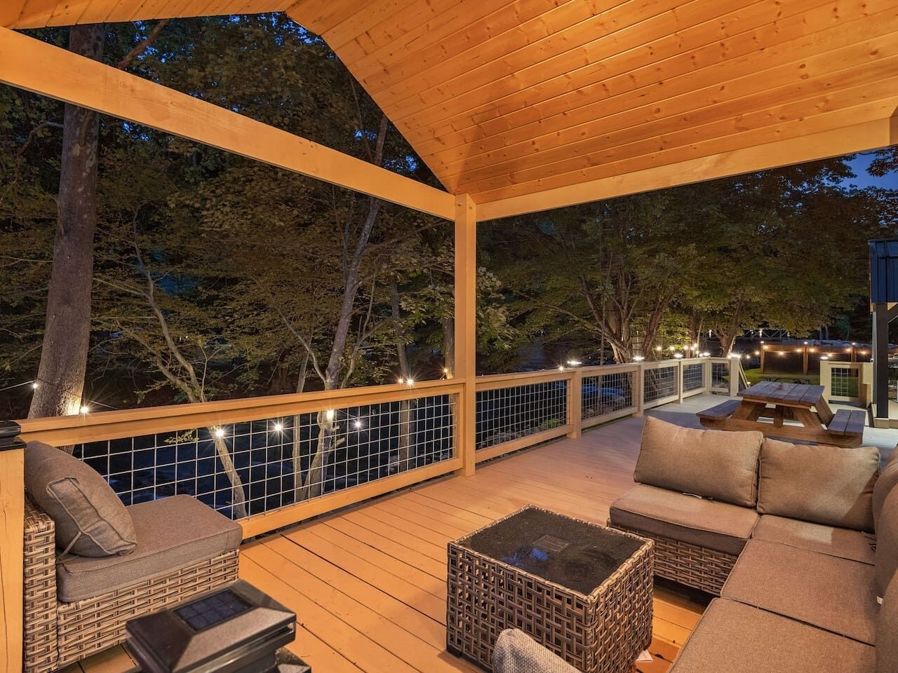 Covered outdoor deck with cozy seating and peaceful wooded views, perfect for relaxing or gathering with friends