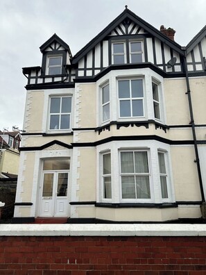 A two-story building with a bay window and a door. - Carmen Sylva 2nd Floor apartment Llandudno (Llandudno)