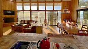 Un amplio espacio de estar con un ventanal grande, paredes de madera, una mesa de comedor y una chimenea.