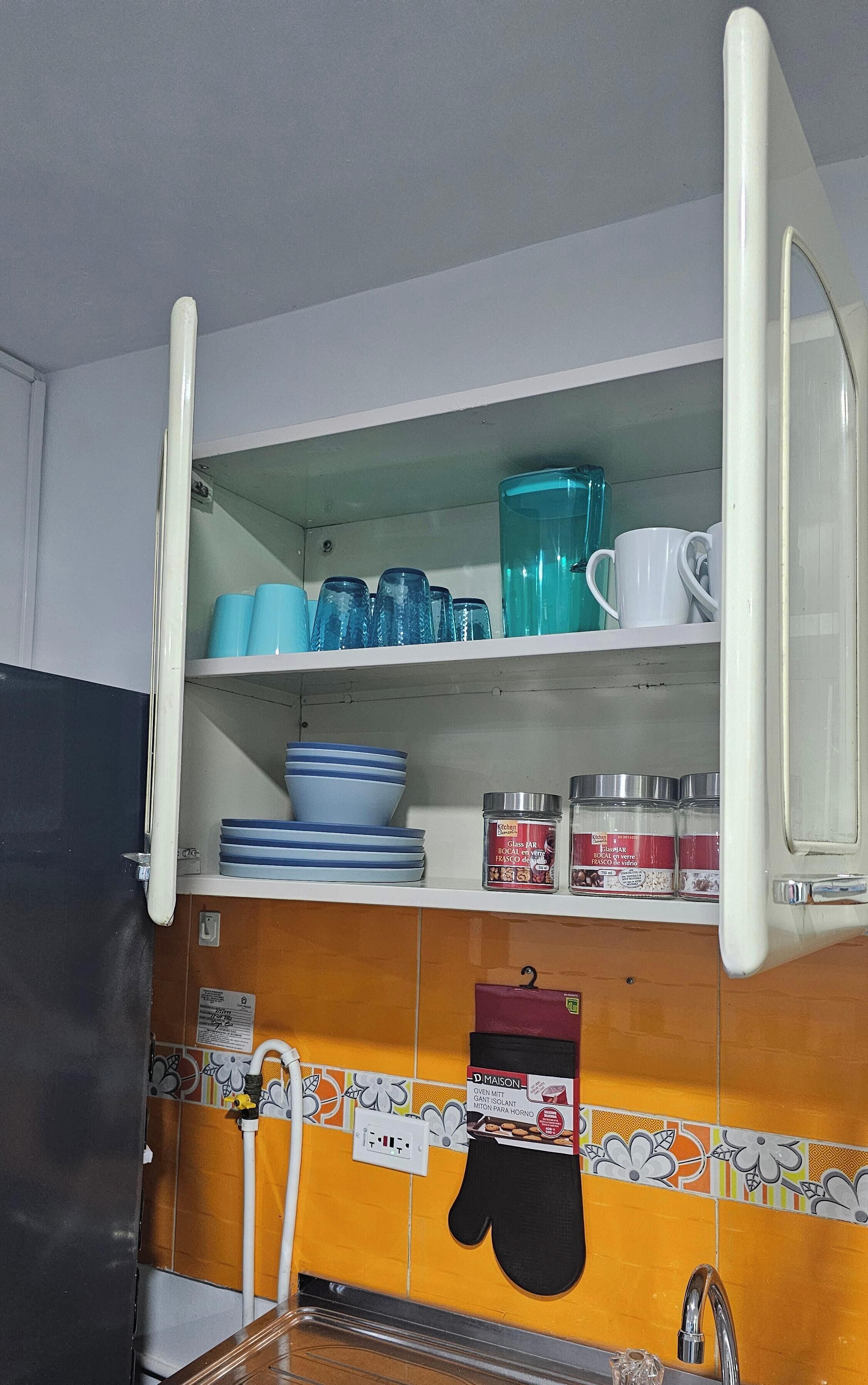 A kitchen with open cabinets displaying dishes and kitchenware.