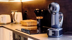 Ett modernt kök med en kaffemaskin, en brödrost och en knivuppsättning på bänkskivan.