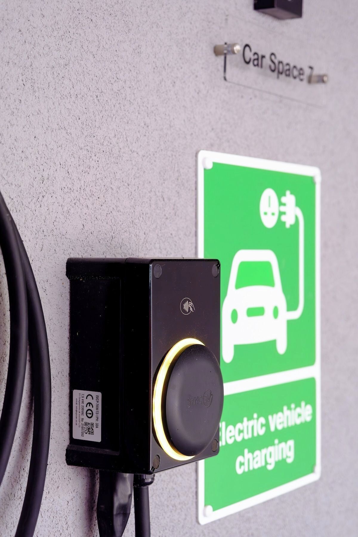 En elbil-ladestation med et skilt der viser 'Parkering 2' og en ladekontakt.