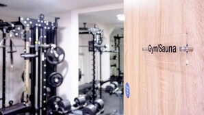 Ett gym med utrustning för styrketräning och en skylt som visar att det finns en bastu.