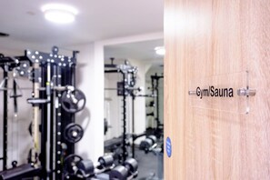 A gym with weightlifting equipment and a sauna sign. - James Court Llandudno Luxury Apartment 2 & Parking (Llandudno)
