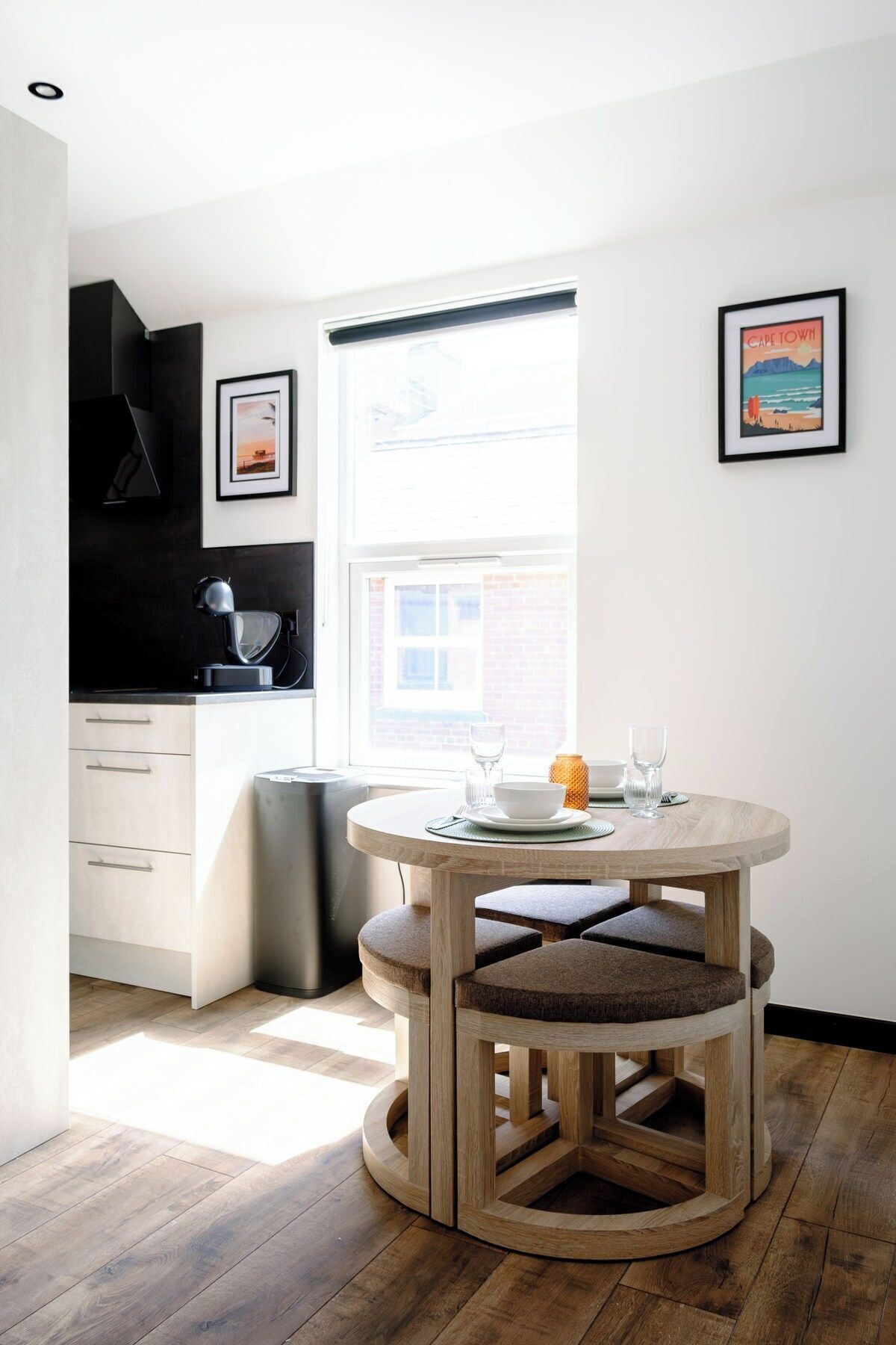 Une cuisine moderne avec une table à manger ronde, des meubles blancs et une fenêtre offrant une belle vue.