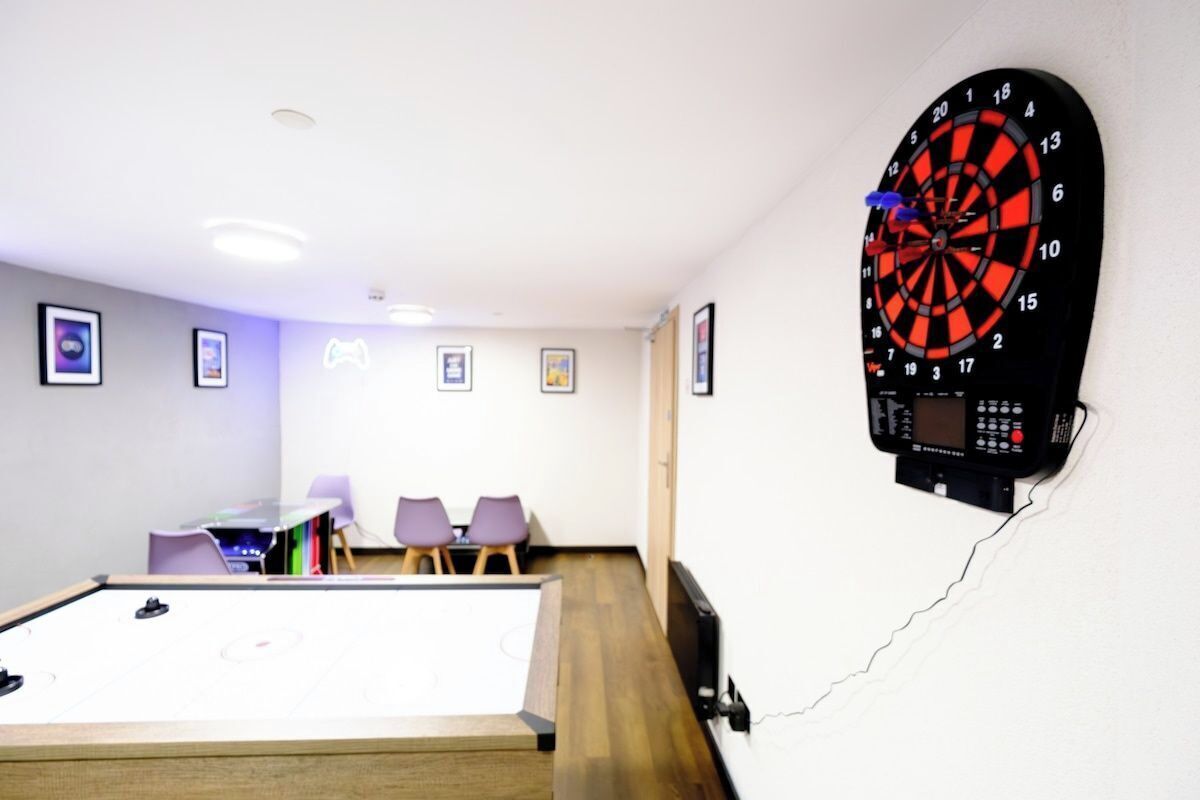 A dartboard mounted on a wall, a pool table, and a seating area with chairs.
