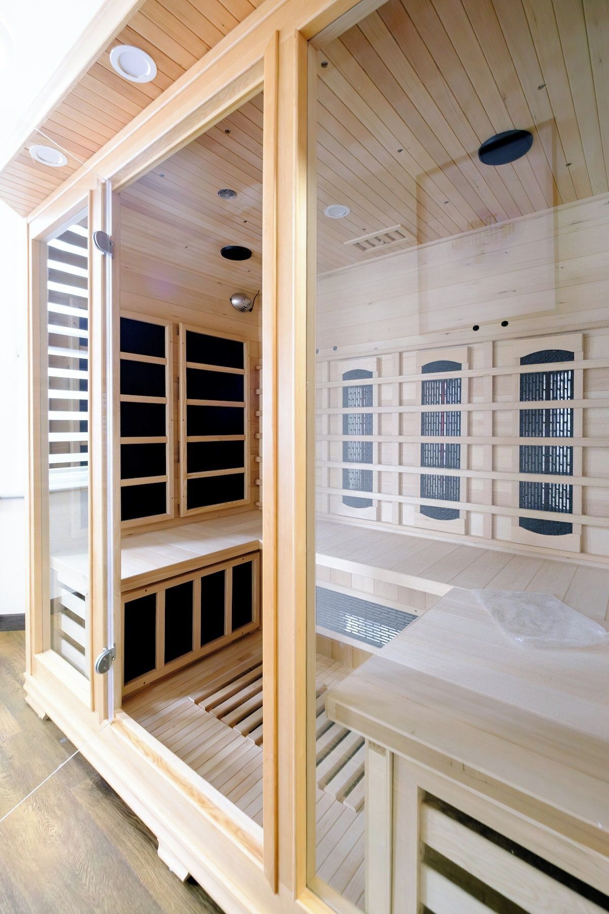 A wooden room with built-in shelves and a bench, featuring a sloped ceiling and a window with blinds.