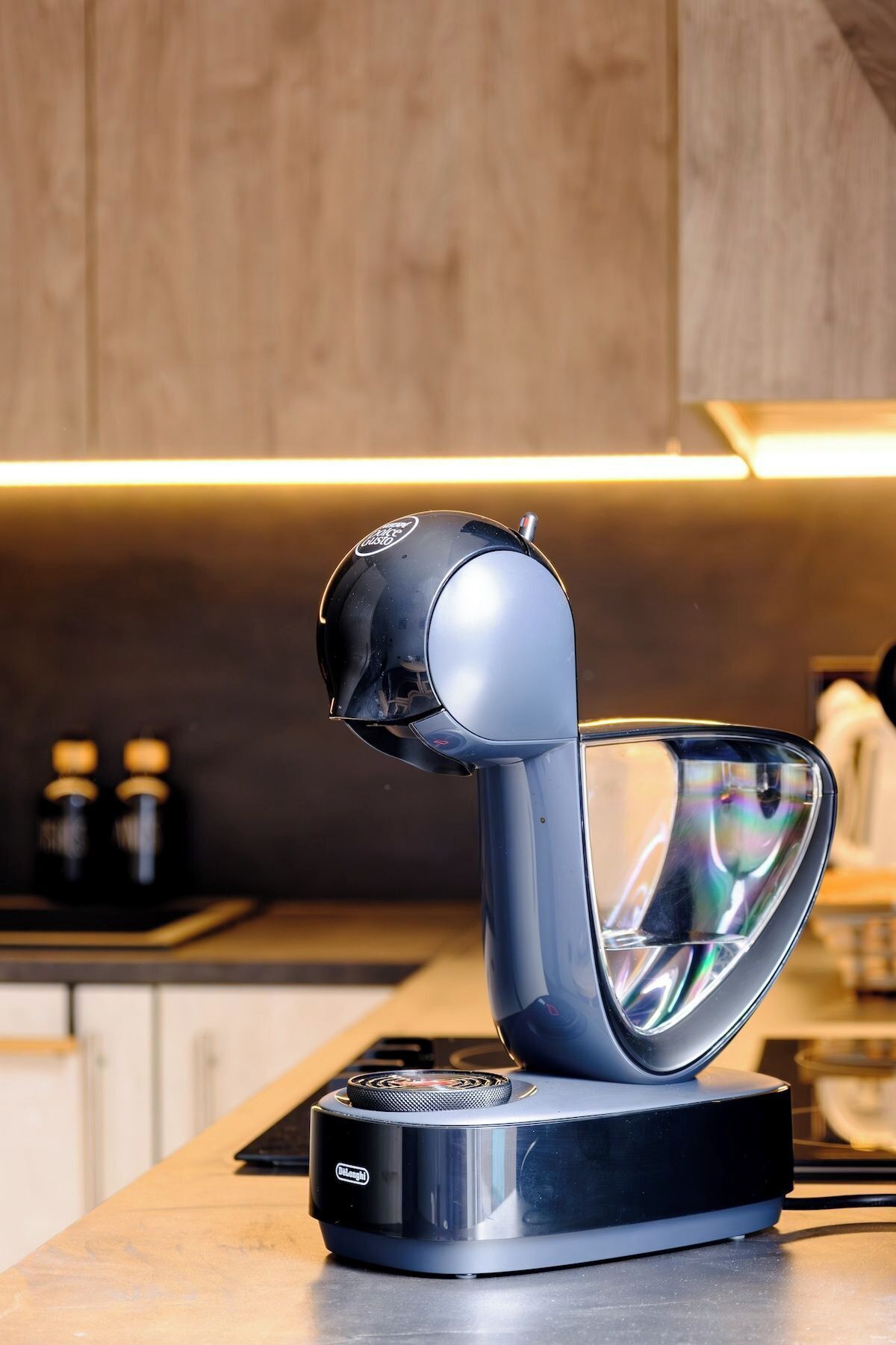 A modern kitchen with a sleek, curved induction cooktop and a compact, black electric kettle.